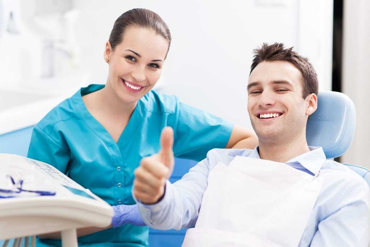 Smiling male patient giving thumbs up during dental consultation with female dentist in Tempe.