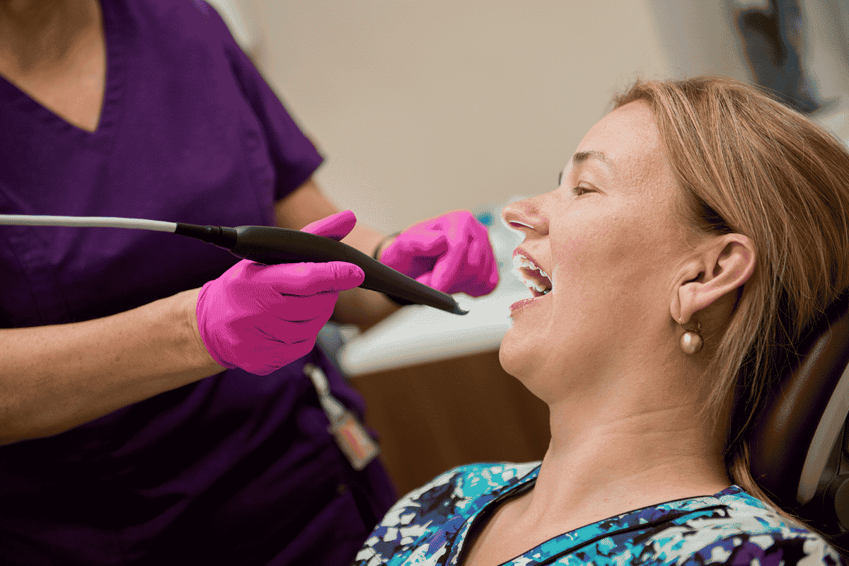 Dentist in purple gloves examining patient's mouth during gum disease evaluation.