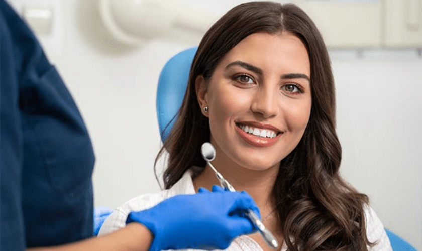 Smiling patient in dental chair wearing blue bib during implant consultation in Tempe.