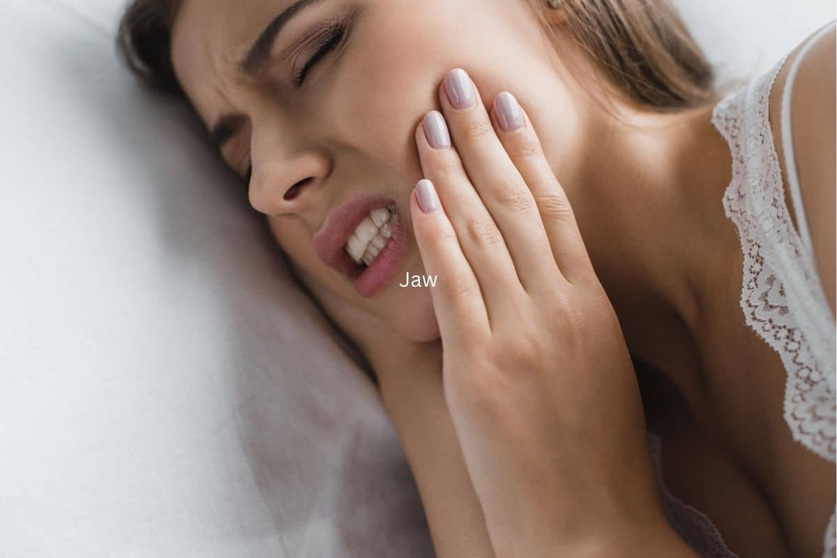 Woman holding jaw in pain, illustrating tooth discomfort and cavity symptoms.