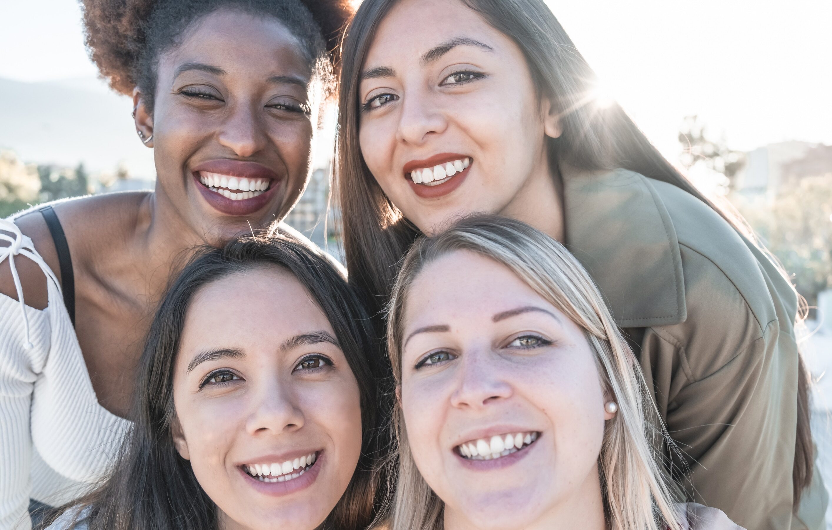 Four diverse women smiling together outdoors in Tempe, Arizona.