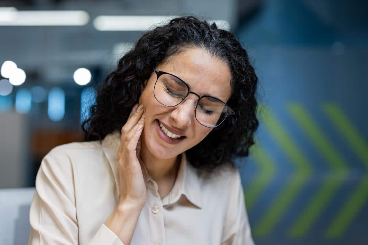 Woman with glasses smiling, experiencing tooth pain relief at Tempe dental practice.