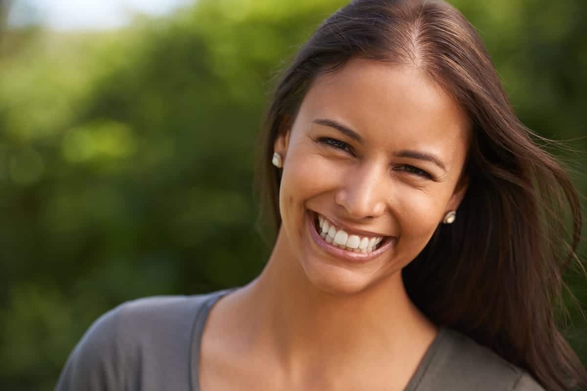 Woman smiling outdoors after dental treatment, showing healthy teeth and confident expression.